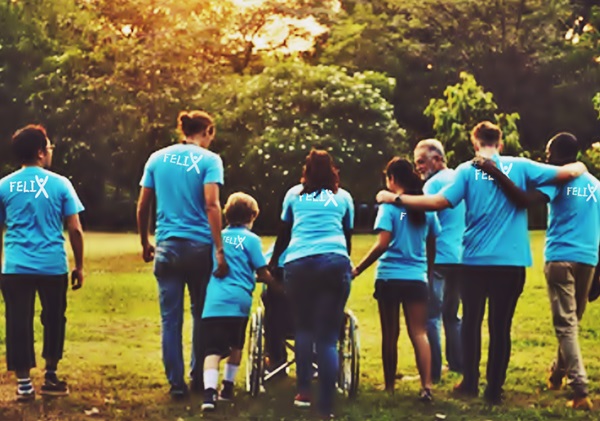 De espaldas, varios voluntarios de uniforme celeste, de ONG Felix fundada por Byron Pernilla, empujan una silla de ruedas.
