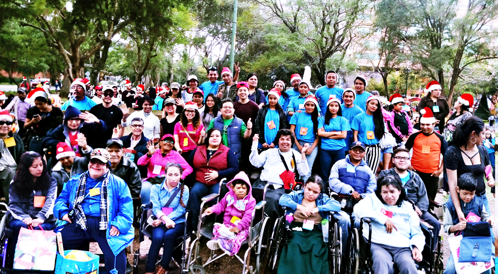 En un parque, se observa a muchas personas con camisa celeste, los volubtarios, y otrases sillade ruedas, los invitados de Byron Pernilla