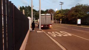 De madrugada, en una calle desierta una voluntaria está a la par de un camión con baños portátiles